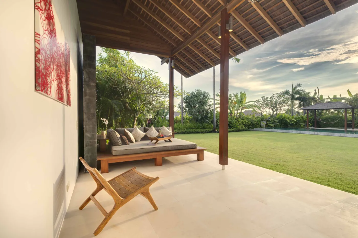 Serene tropical outdoor deck in a Bali villa featuring a stone bathtub filled with rose petals, lounge chairs, towels, and lush greenery. - Bali Villas