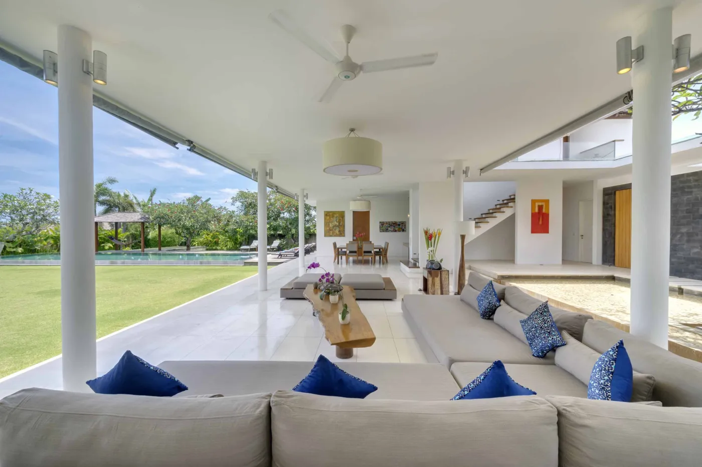 Serene tropical outdoor deck in a Bali villa featuring a stone bathtub filled with rose petals, lounge chairs, towels, and lush greenery. - Bali Villas