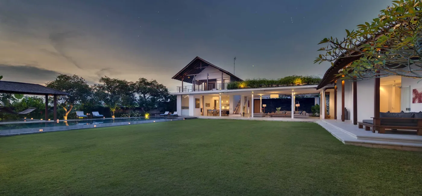 Serene tropical outdoor deck in a Bali villa featuring a stone bathtub filled with rose petals, lounge chairs, towels, and lush greenery. - Bali Villas