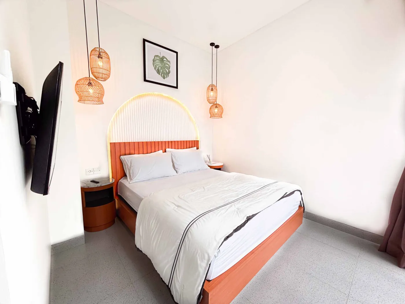 Modern tropical villa kitchen and dining area with orange cabinets, wooden ceiling, pendant lights, and outdoor pool view featuring a statue. - Bali Villas