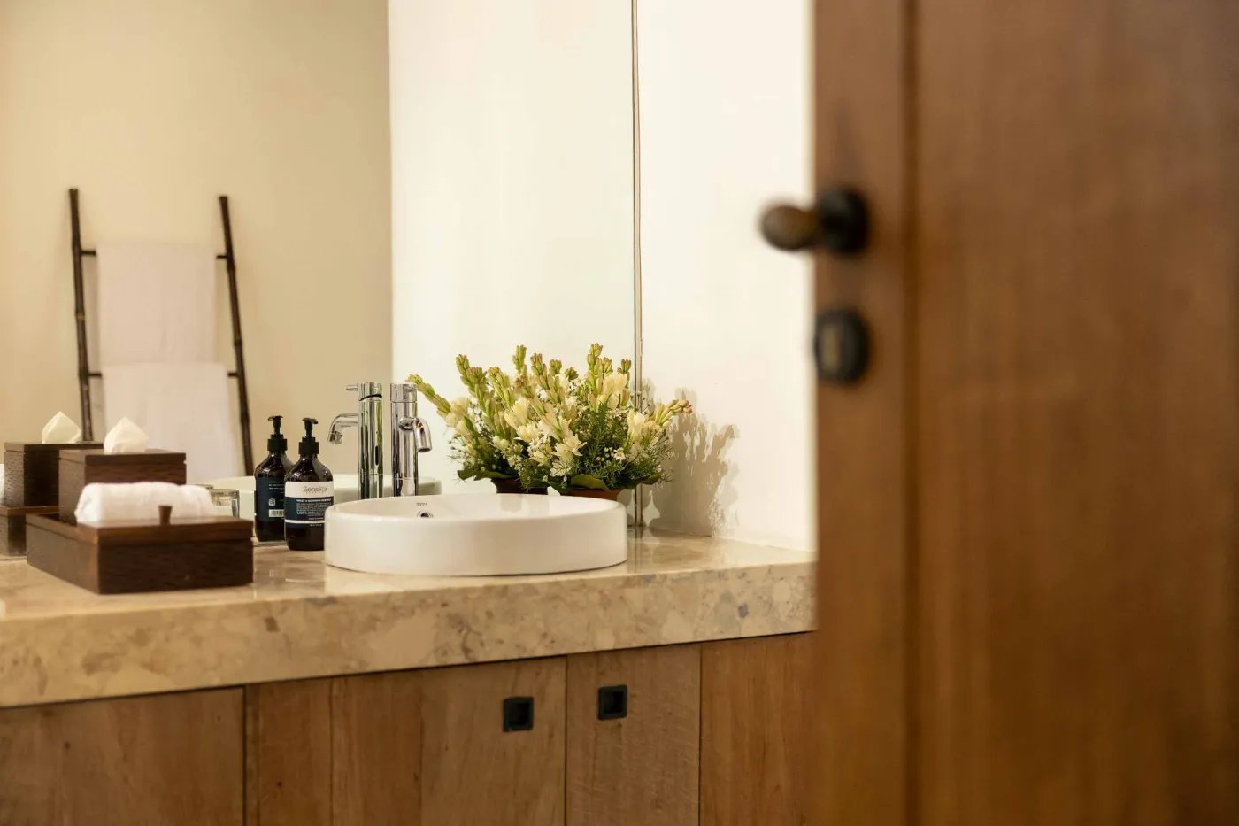 Spacious open-plan living and dining area in a modern tropical villa with exposed wooden beams, white walls, hardwood floors, and large windows. - Bali Villas