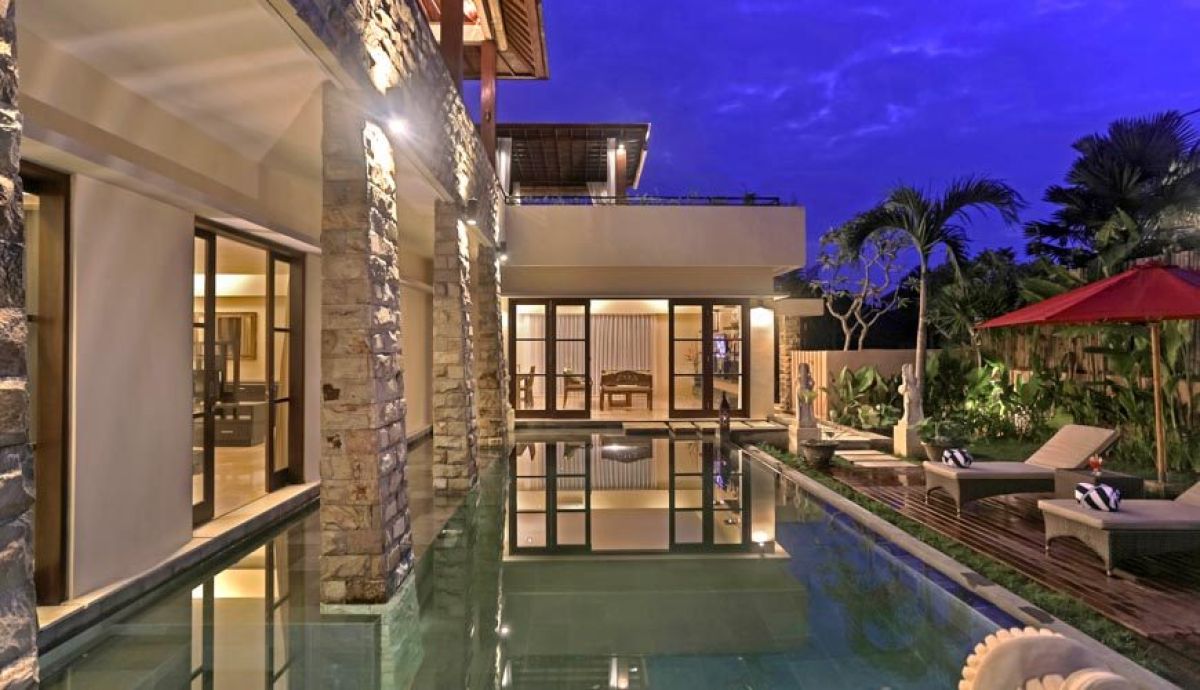 Luxurious wooden pergola with sheer white curtains on a tropical rooftop at sunset, curved lounge sofa, plants, and Balinese village view. - Bali Villas
