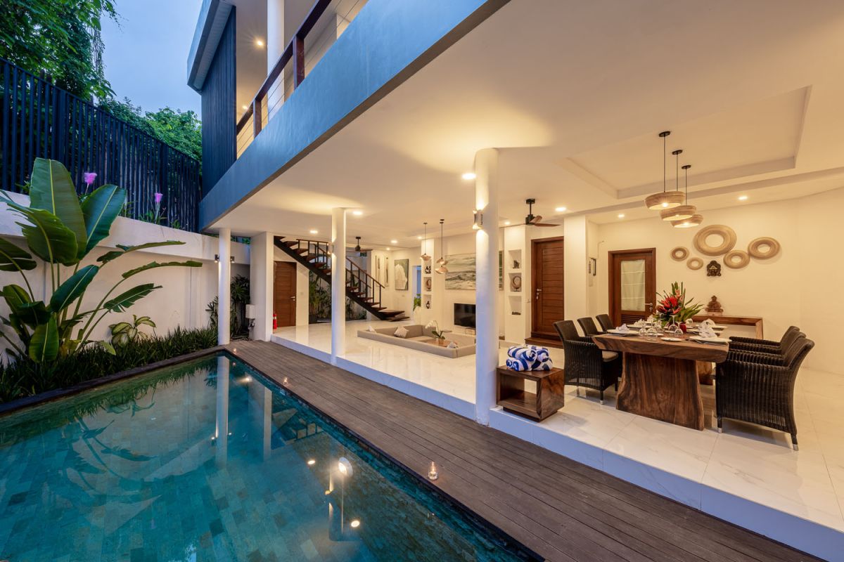 Modern luxury bathroom with freestanding bathtub filled with petals, double vessel sink vanity, glass shower, and tropical accents. - Bali Villas
