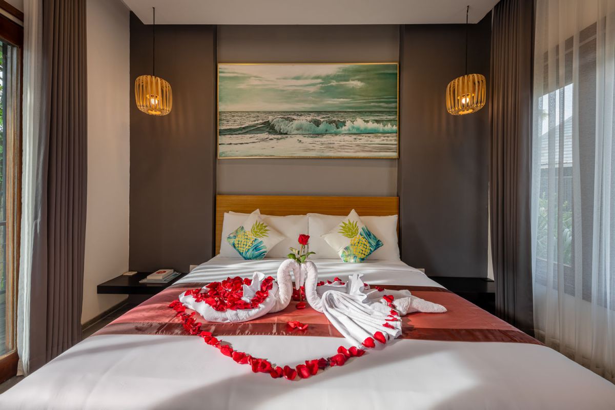 Modern luxury bathroom with freestanding bathtub filled with petals, double vessel sink vanity, glass shower, and tropical accents. - Bali Villas