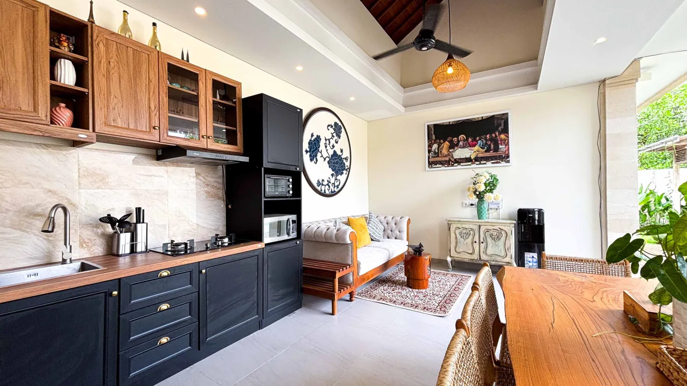 Modern bathroom with gray tile walls, corner soaking tub, wooden vanity sink, towel ladder, and rustic reclaimed wood door. - Bali Villas