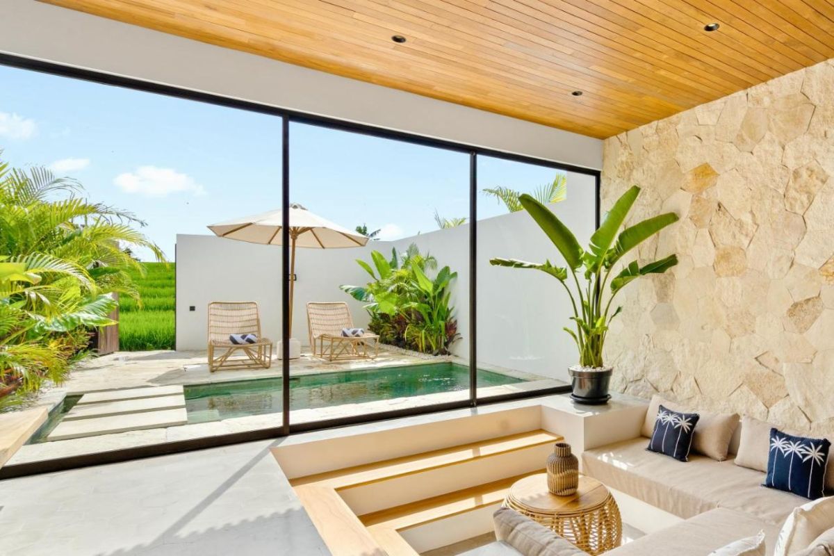 Modern tropical kitchen interior with wooden dining table, rattan pendant lights, woven wall art, and fresh flowers. - Bali Villas