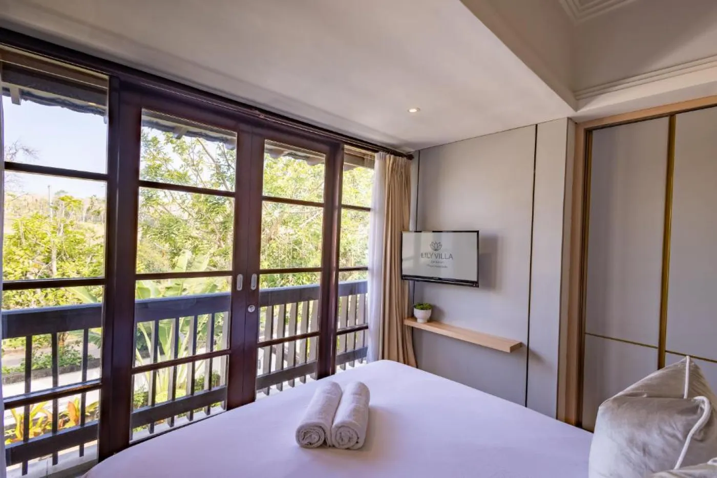 Modern en-suite bathroom featuring white vanity sink, glass shower enclosure, and adjacent mirrored wardrobe on beige tiled floor. - Bali Villas