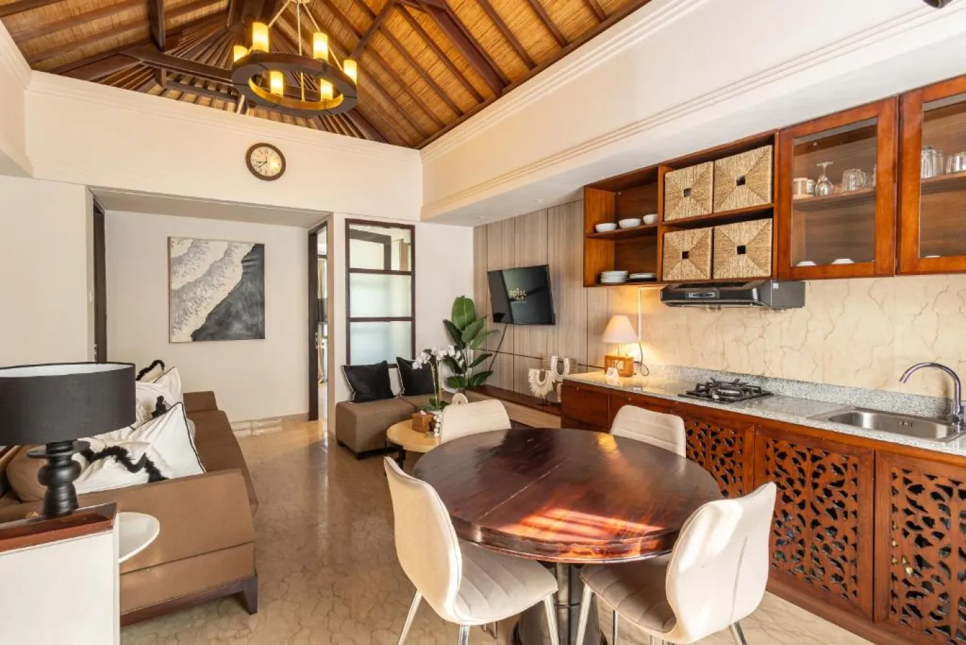 Modern en-suite bathroom featuring white vanity sink, glass shower enclosure, and adjacent mirrored wardrobe on beige tiled floor. - Bali Villas