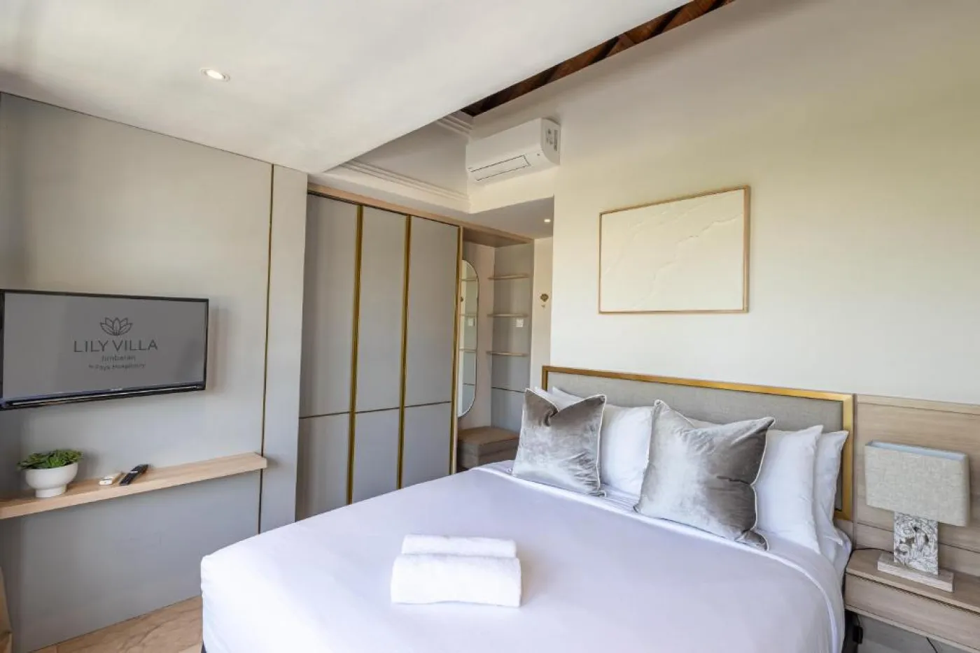 Modern en-suite bathroom featuring white vanity sink, glass shower enclosure, and adjacent mirrored wardrobe on beige tiled floor. - Bali Villas
