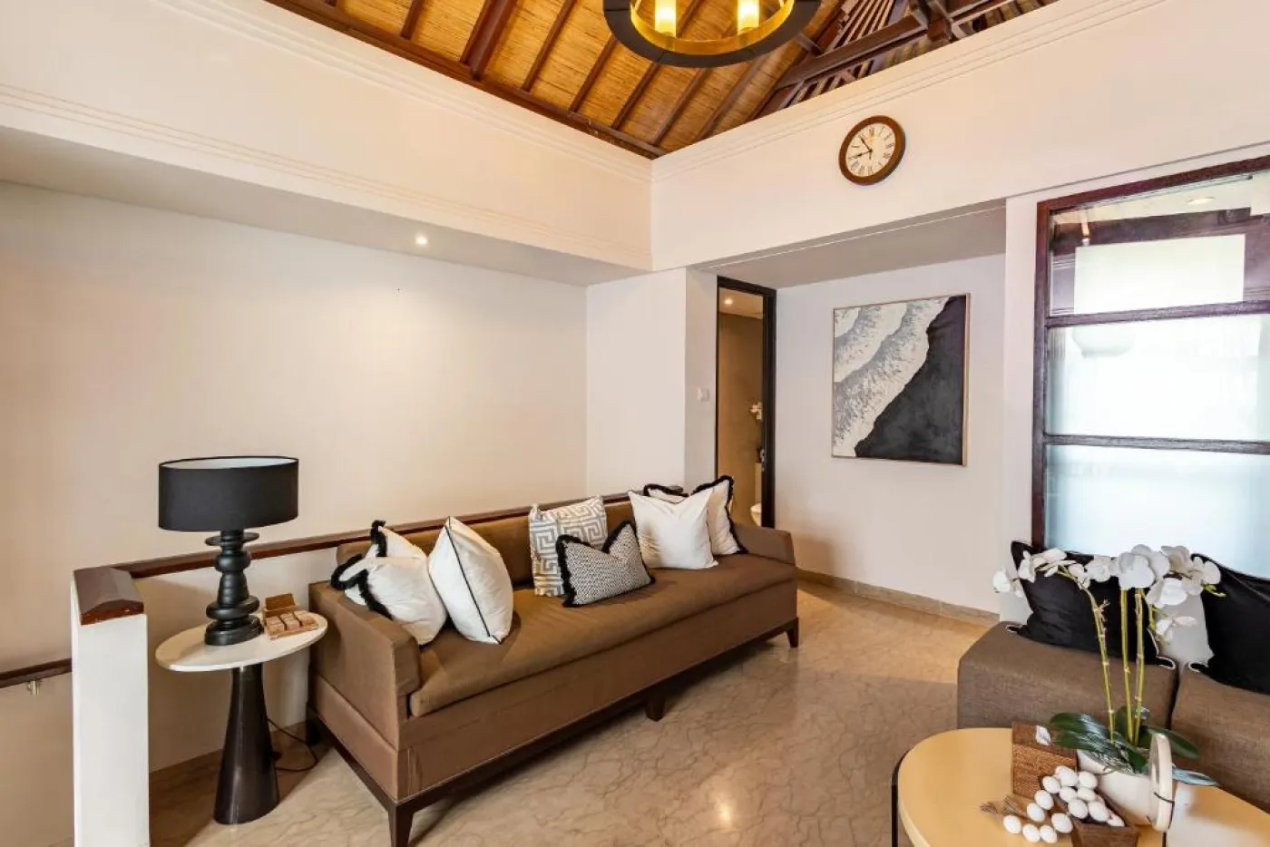Modern en-suite bathroom featuring white vanity sink, glass shower enclosure, and adjacent mirrored wardrobe on beige tiled floor. - Bali Villas