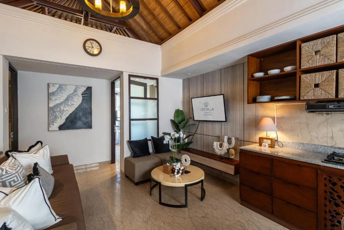 Modern en-suite bathroom featuring white vanity sink, glass shower enclosure, and adjacent mirrored wardrobe on beige tiled floor. - Bali Villas