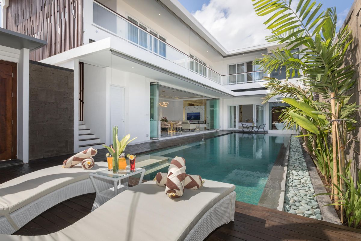 Modern luxury kitchen with glossy turquoise cabinets, marble counters, built-in appliances, and pendant lighting. - Bali Villas