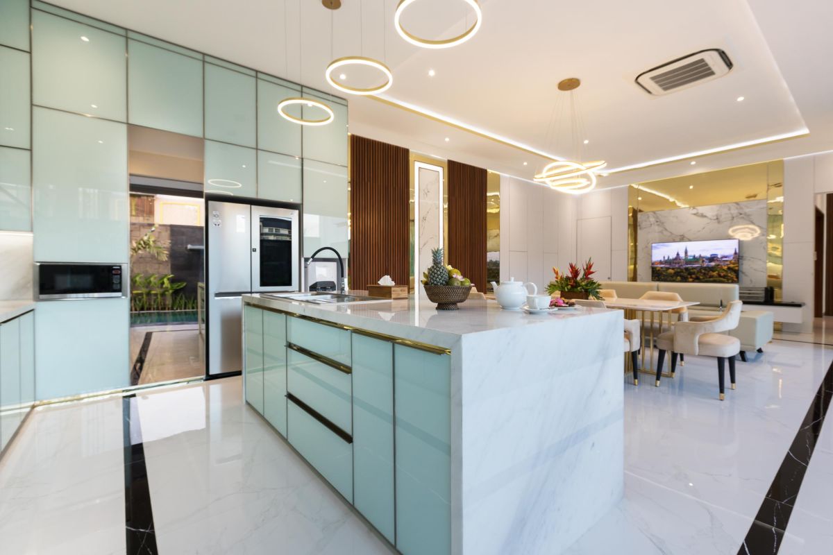Modern luxury kitchen with glossy turquoise cabinets, marble counters, built-in appliances, and pendant lighting. - Bali Villas