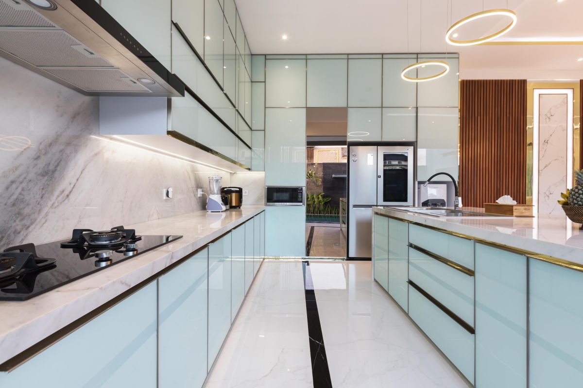 Modern luxury kitchen with glossy turquoise cabinets, marble counters, built-in appliances, and pendant lighting. - Bali Villas