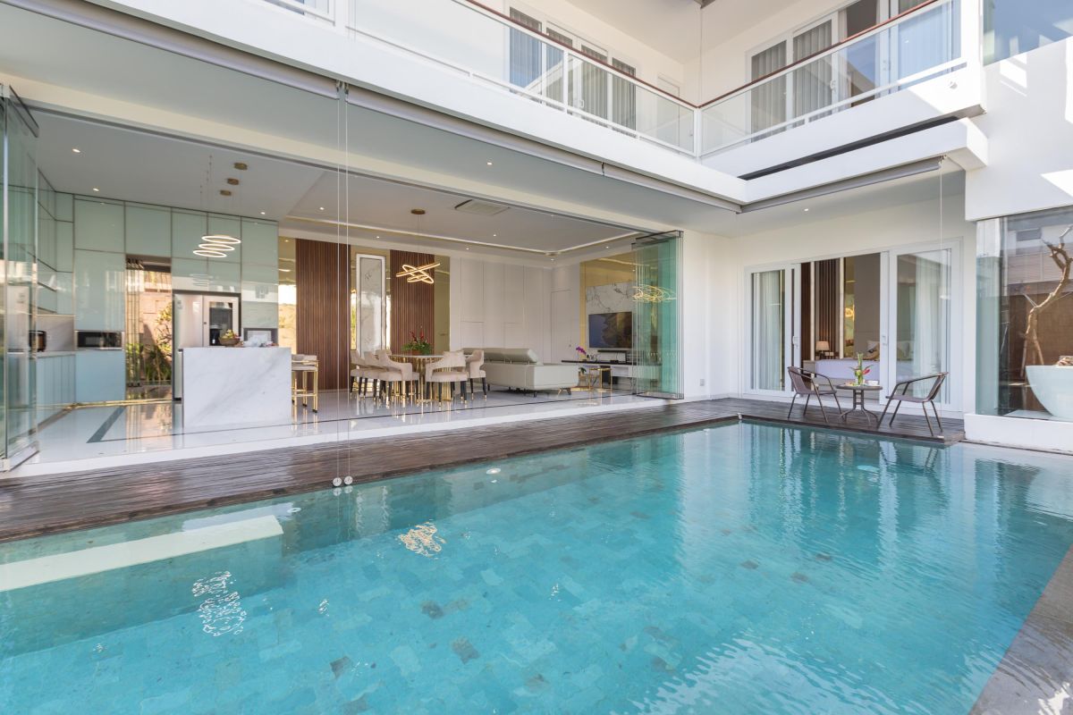 Modern luxury kitchen with glossy turquoise cabinets, marble counters, built-in appliances, and pendant lighting. - Bali Villas