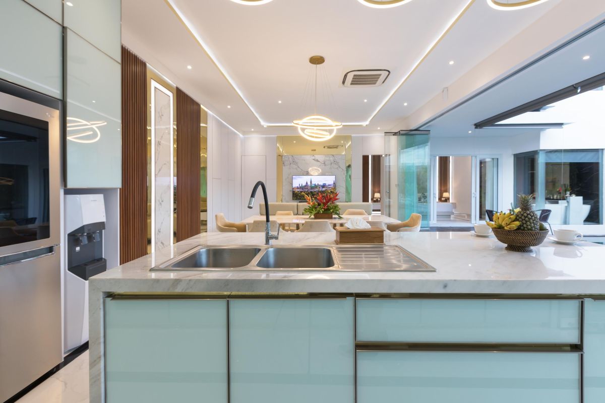Modern luxury kitchen with glossy turquoise cabinets, marble counters, built-in appliances, and pendant lighting. - Bali Villas