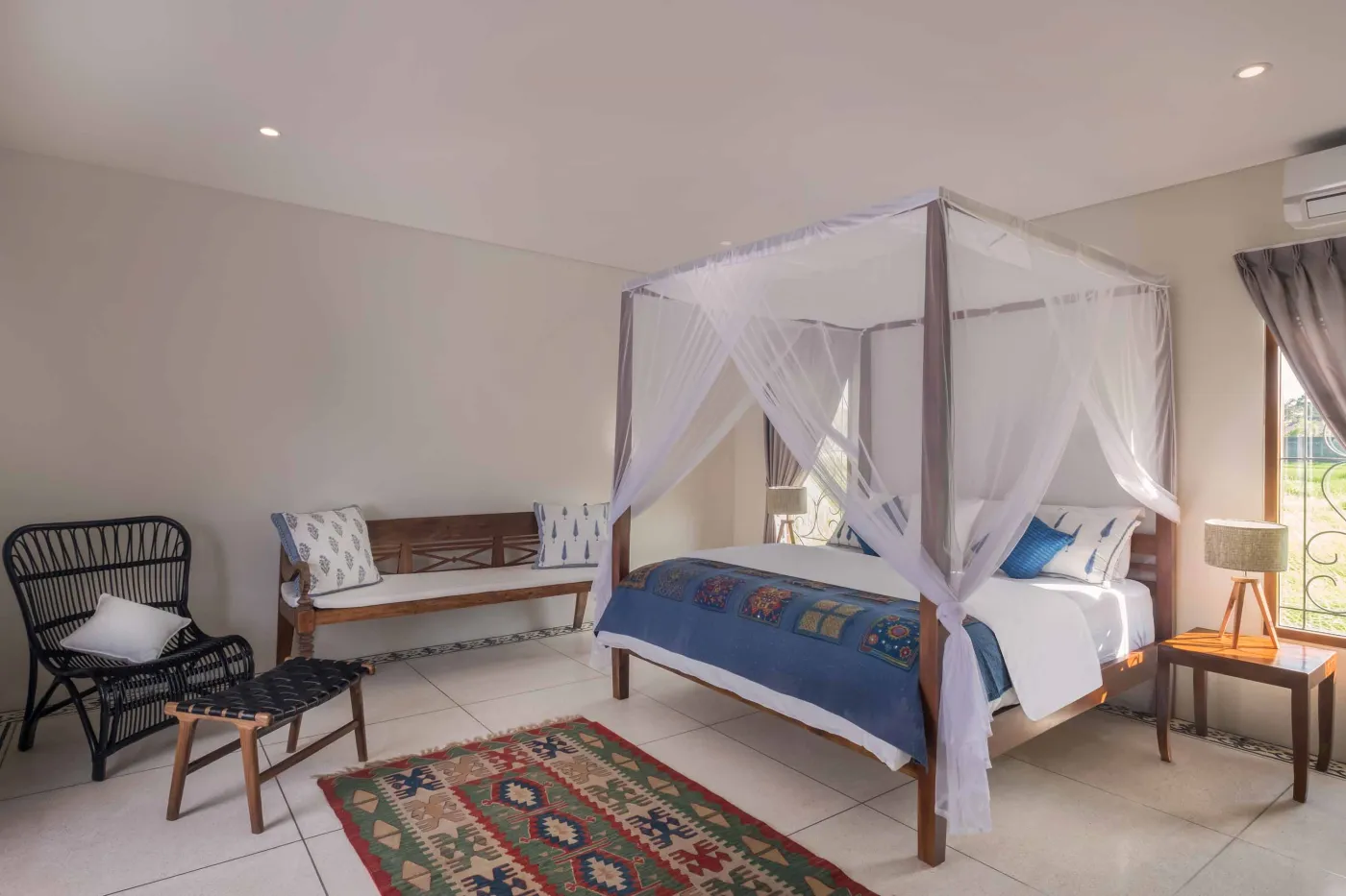 Modern Balinese villa with open-plan living room featuring white sofa, large glass doors to lush garden path, wooden accents, and red-tiled upper level. - Bali Villas