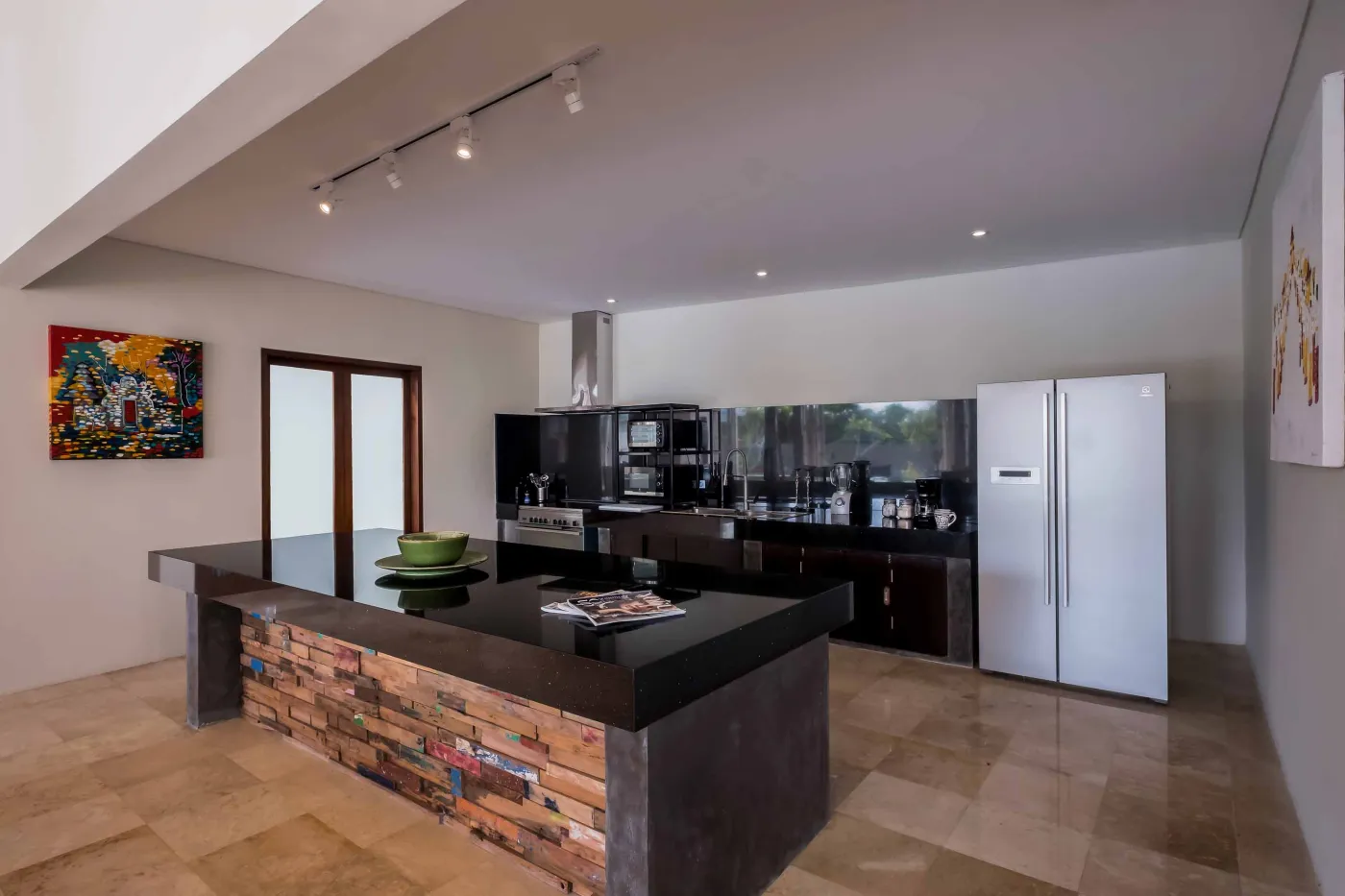 Modern Balinese villa with open-plan living room featuring white sofa, large glass doors to lush garden path, wooden accents, and red-tiled upper level. - Bali Villas
