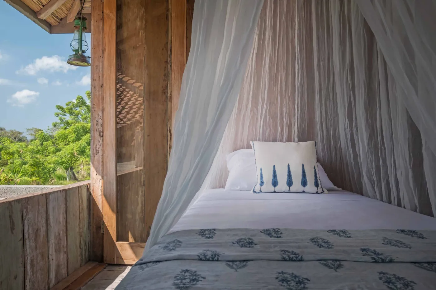 Modern Balinese villa with open-plan living room featuring white sofa, large glass doors to lush garden path, wooden accents, and red-tiled upper level. - Bali Villas