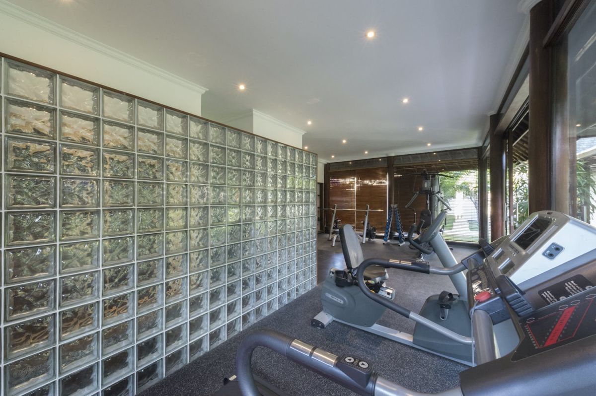 Spacious luxury Bali villa bedroom with king bed, modern black furniture, large abstract wall art, and panoramic balcony view of tropical greenery. - Bali Villas