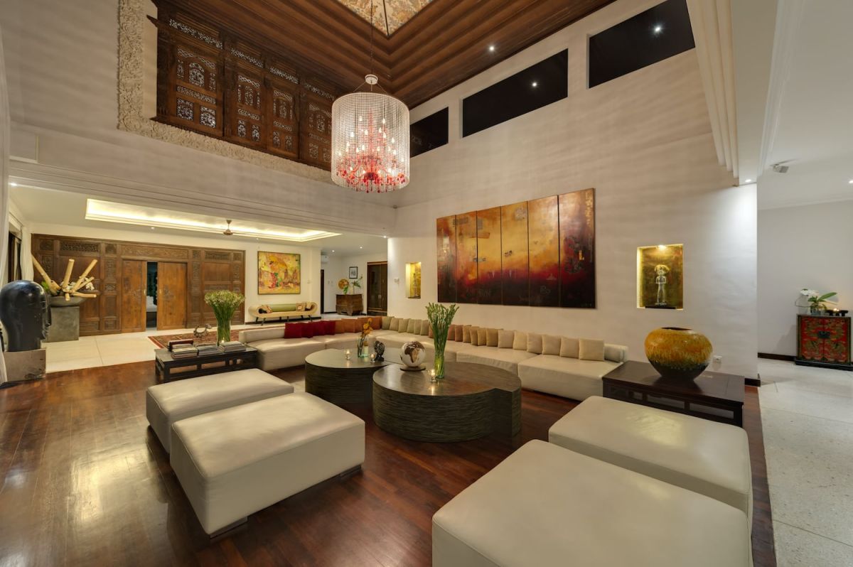 Spacious luxury Bali villa bedroom with king bed, modern black furniture, large abstract wall art, and panoramic balcony view of tropical greenery. - Bali Villas
