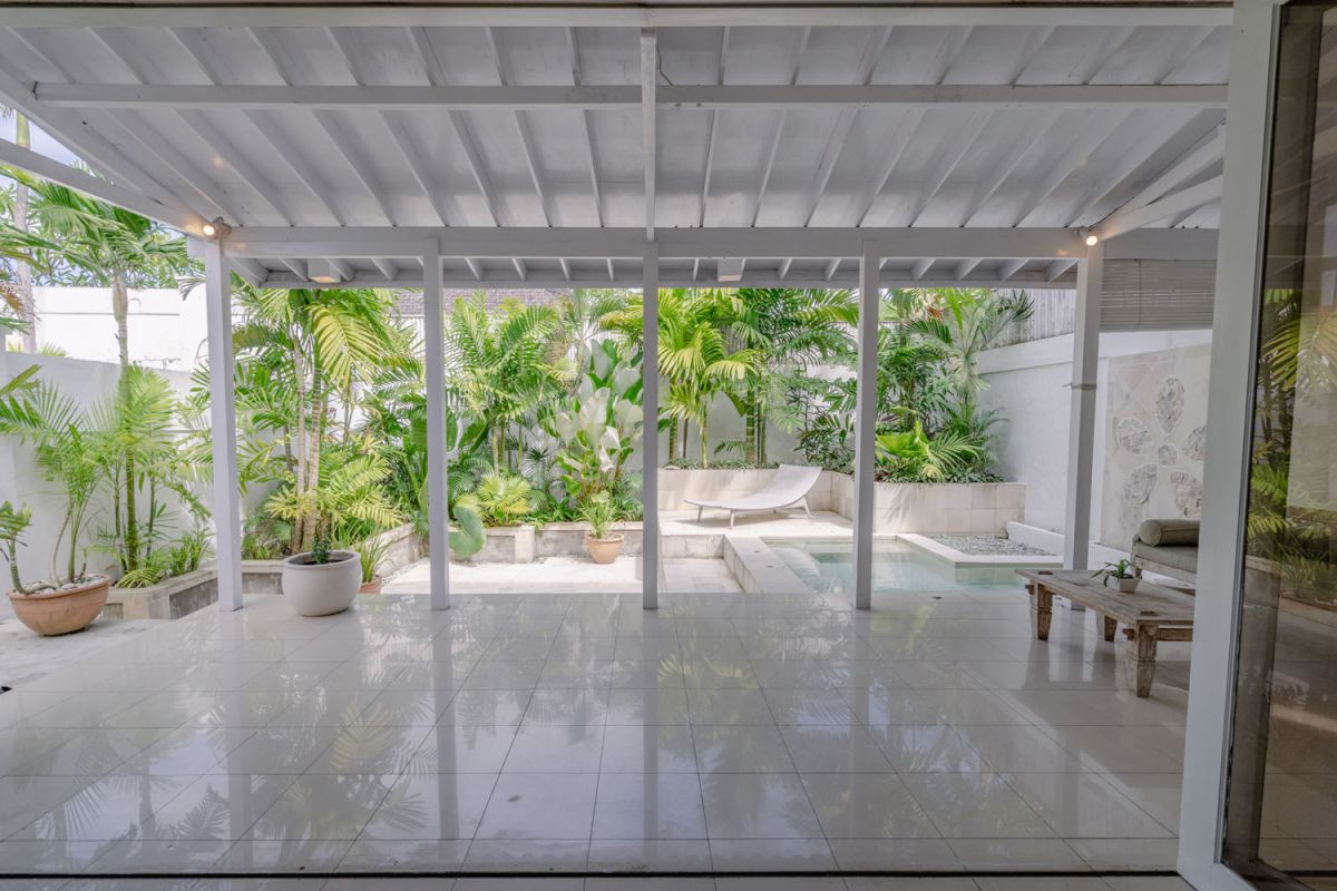 Bright tropical kitchenette with white countertops, fruit platter, louvered cabinets, fridge, and warm lamp lighting. - Bali Villas