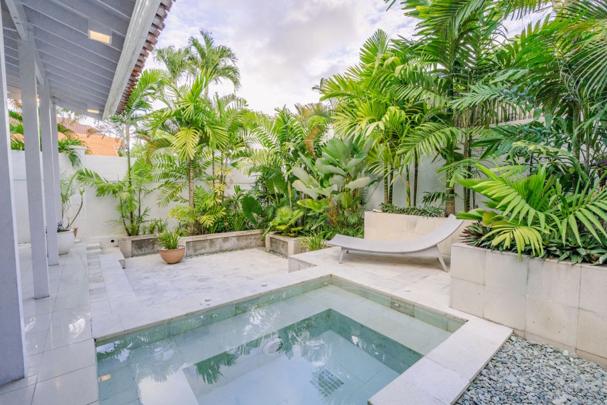Bright tropical kitchenette with white countertops, fruit platter, louvered cabinets, fridge, and warm lamp lighting. - Bali Villas