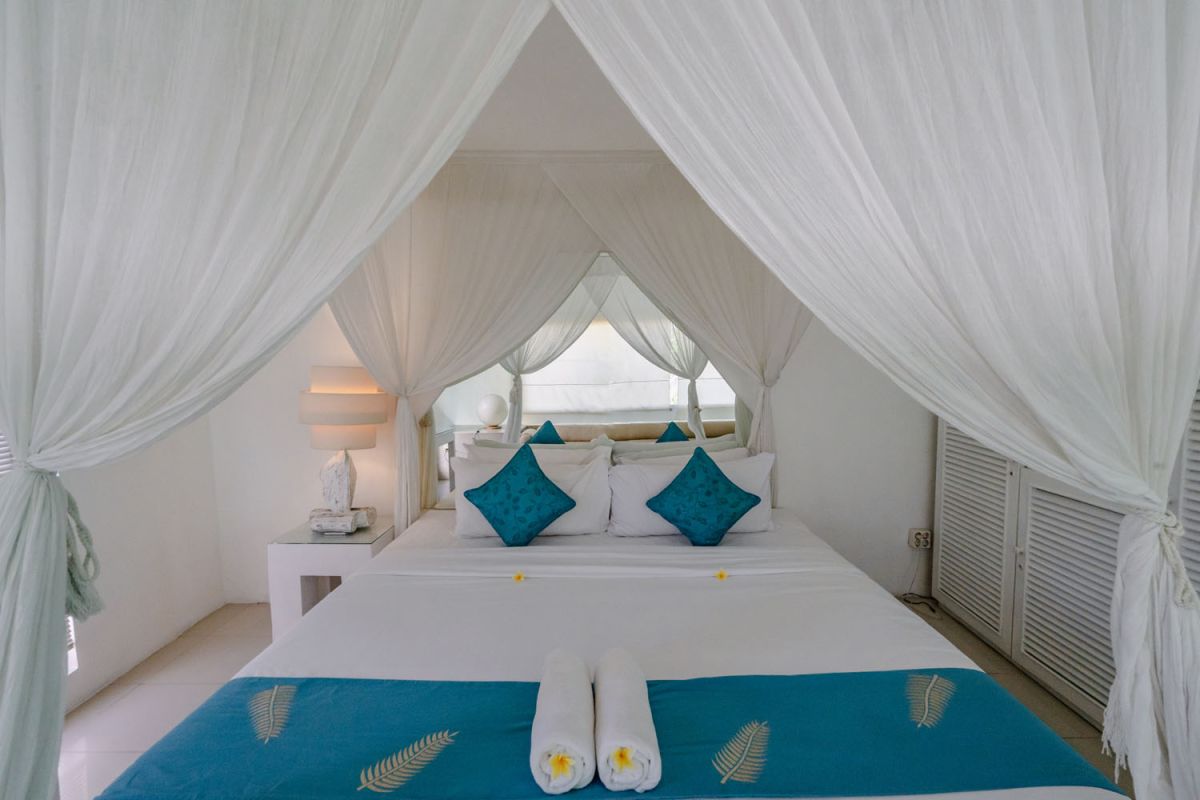 Bright tropical kitchenette with white countertops, fruit platter, louvered cabinets, fridge, and warm lamp lighting. - Bali Villas