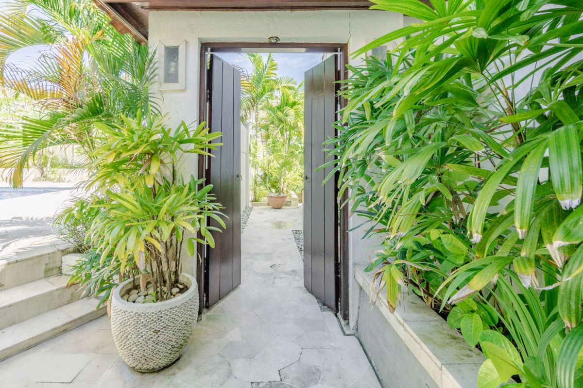Bright tropical kitchenette with white countertops, fruit platter, louvered cabinets, fridge, and warm lamp lighting. - Bali Villas