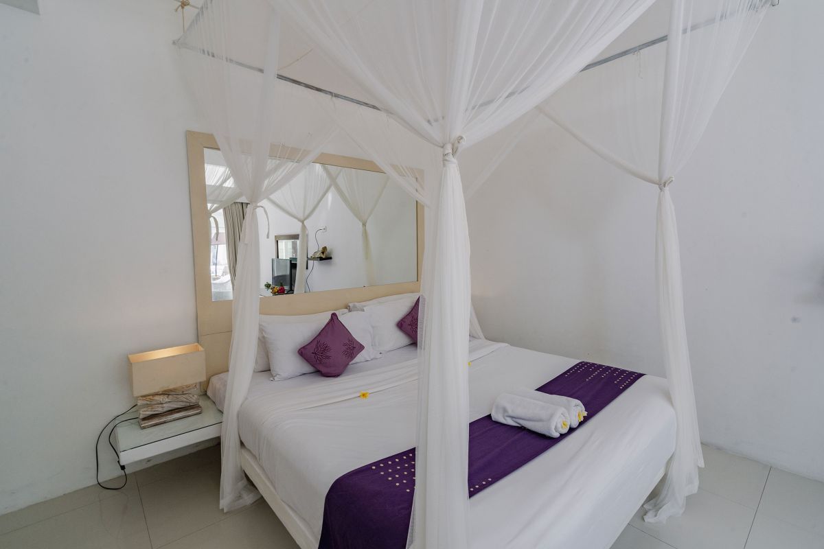 Compact modern bathroom interior with white tiled walls, toilet, sink vanity, and decorative flowers. - Bali Villas