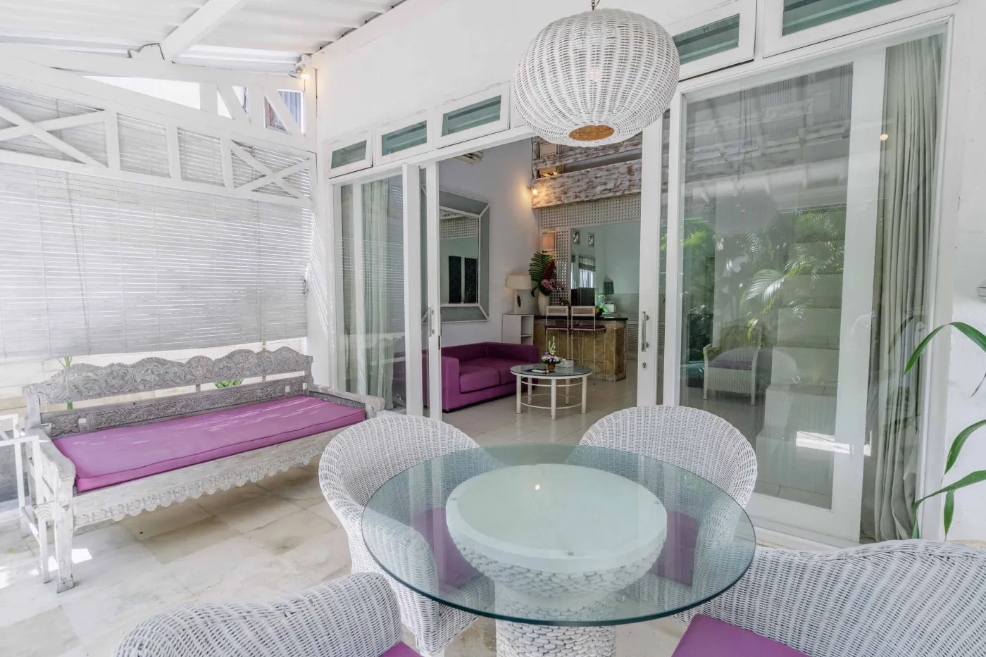 Modern bathroom interior with beige tiled walls, large frameless mirror, white vanity sink, toiletries, and walk-in shower. - Bali Villas