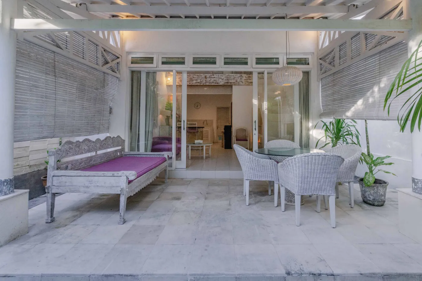 Modern bathroom interior with beige tiled walls, large frameless mirror, white vanity sink, toiletries, and walk-in shower. - Bali Villas