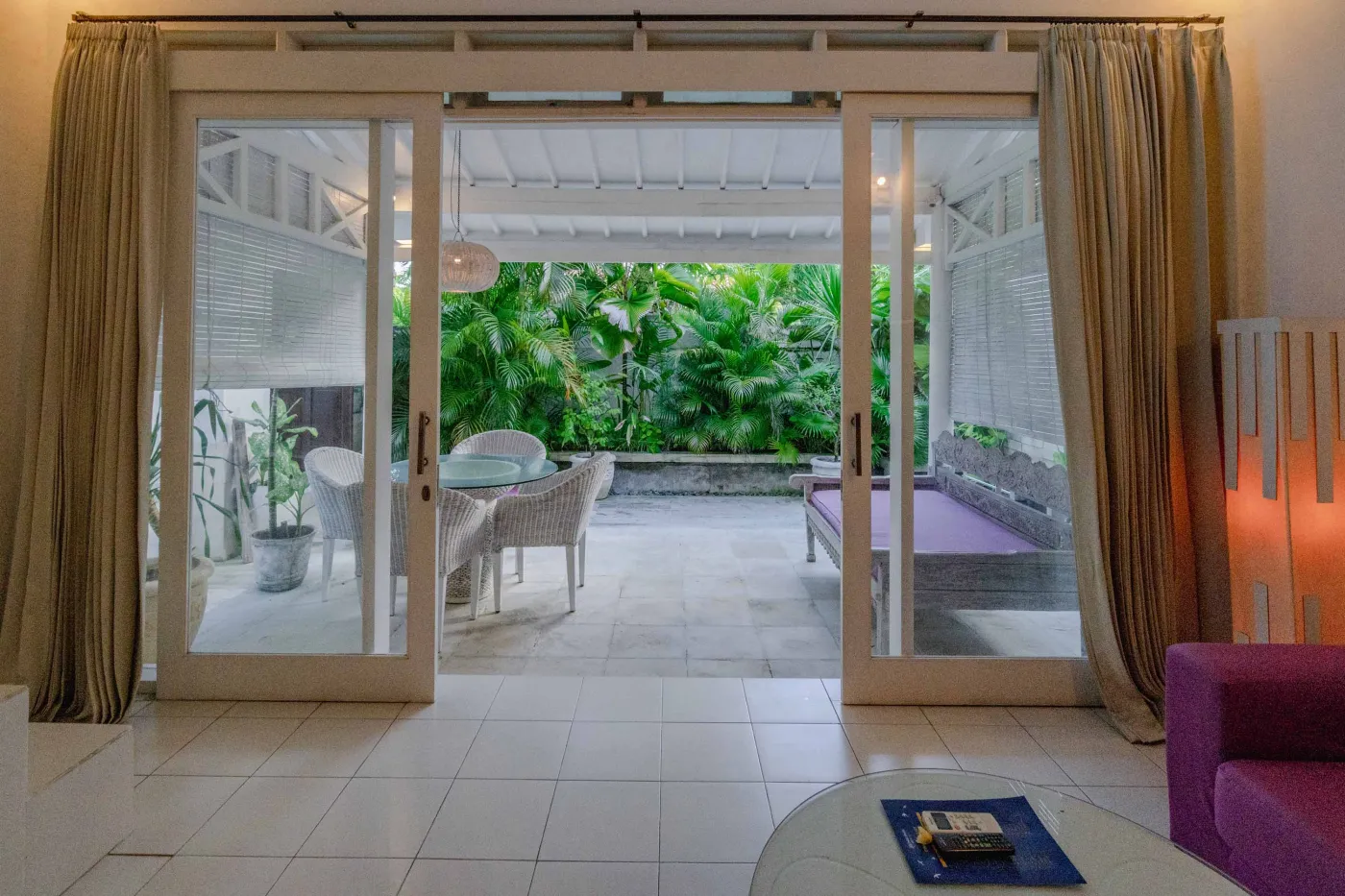 Modern bathroom interior with beige tiled walls, large frameless mirror, white vanity sink, toiletries, and walk-in shower. - Bali Villas