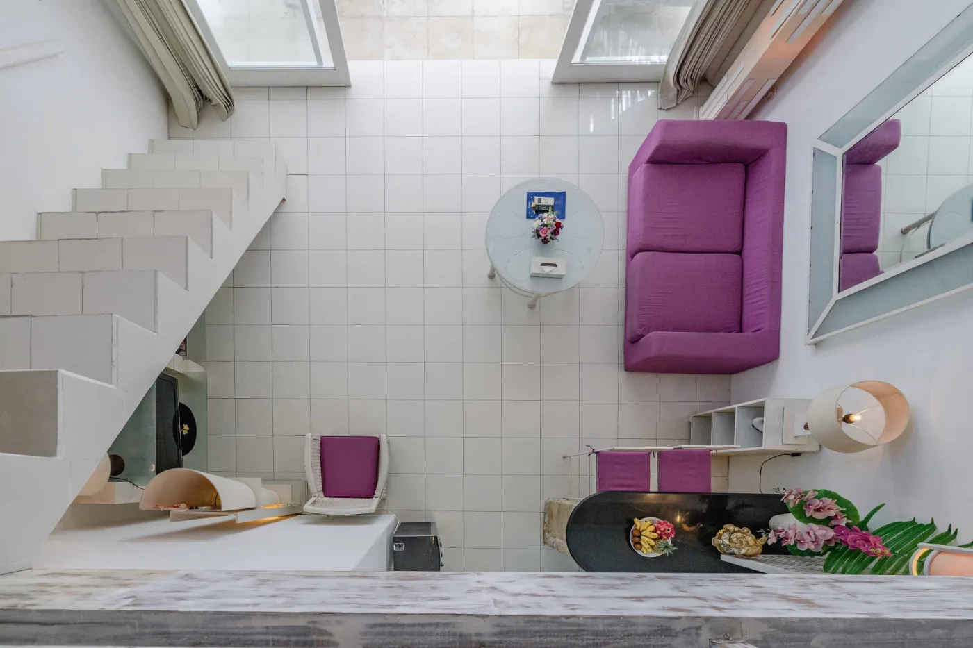 Modern bathroom interior with beige tiled walls, large frameless mirror, white vanity sink, toiletries, and walk-in shower. - Bali Villas