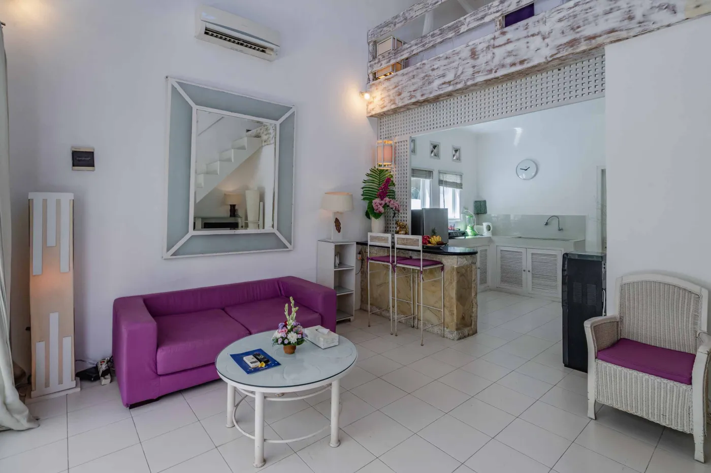 Modern bathroom interior with beige tiled walls, large frameless mirror, white vanity sink, toiletries, and walk-in shower. - Bali Villas
