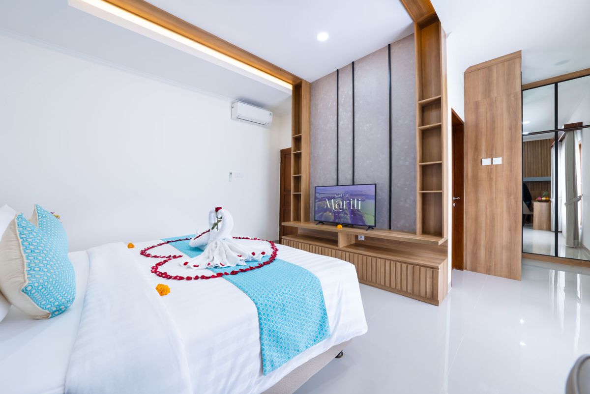 Spacious modern kitchen and dining area with wooden table set for meals, open cabinetry, and sliding glass doors to pool. - Bali Villas