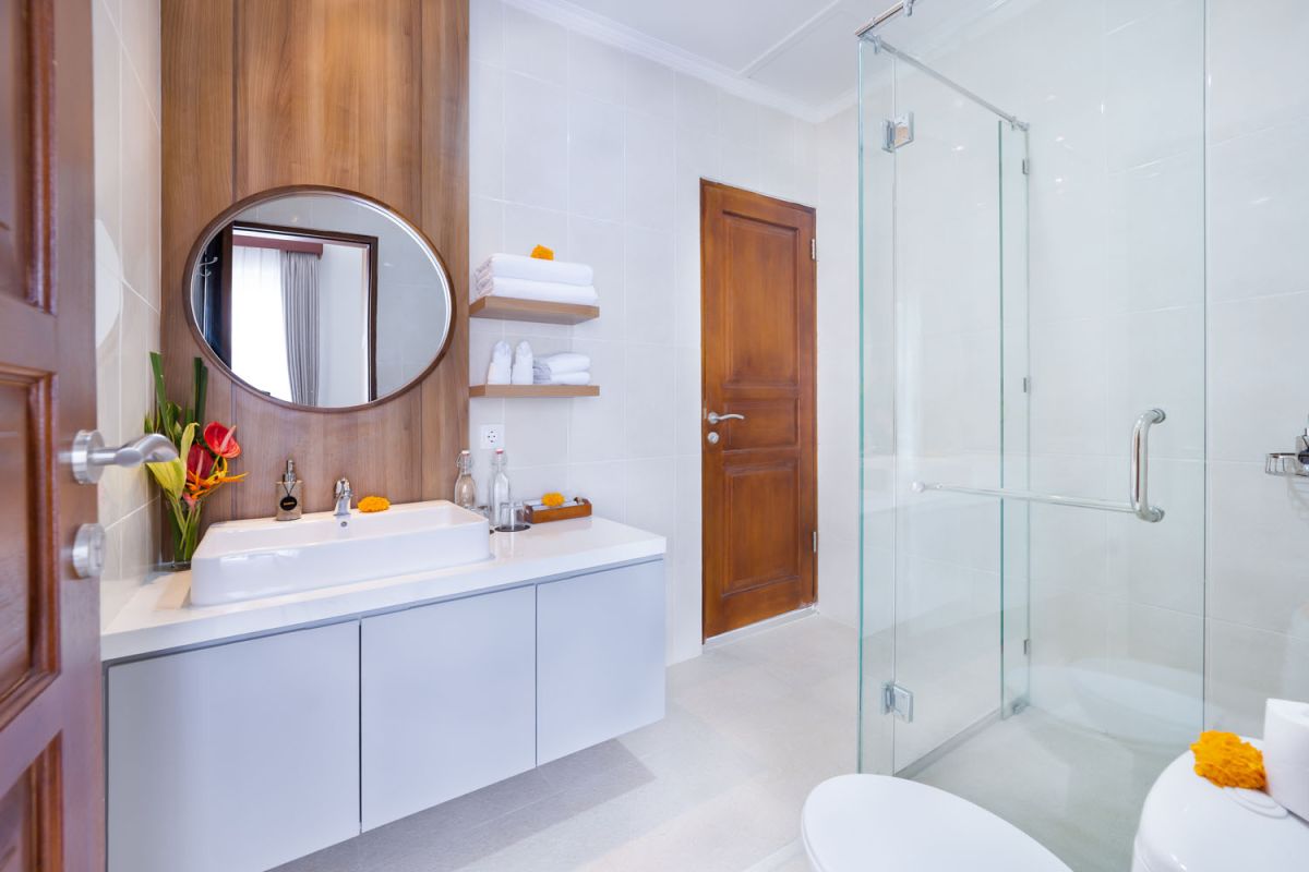 Spacious modern kitchen and dining area with wooden table set for meals, open cabinetry, and sliding glass doors to pool. - Bali Villas