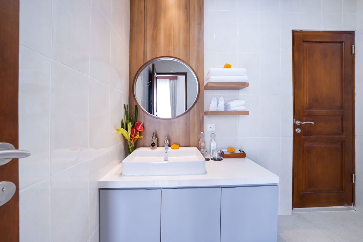 Spacious modern kitchen and dining area with wooden table set for meals, open cabinetry, and sliding glass doors to pool. - Bali Villas