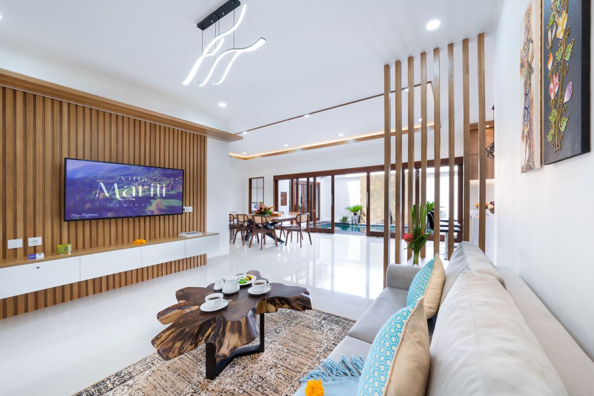 Spacious modern kitchen and dining area with wooden table set for meals, open cabinetry, and sliding glass doors to pool. - Bali Villas