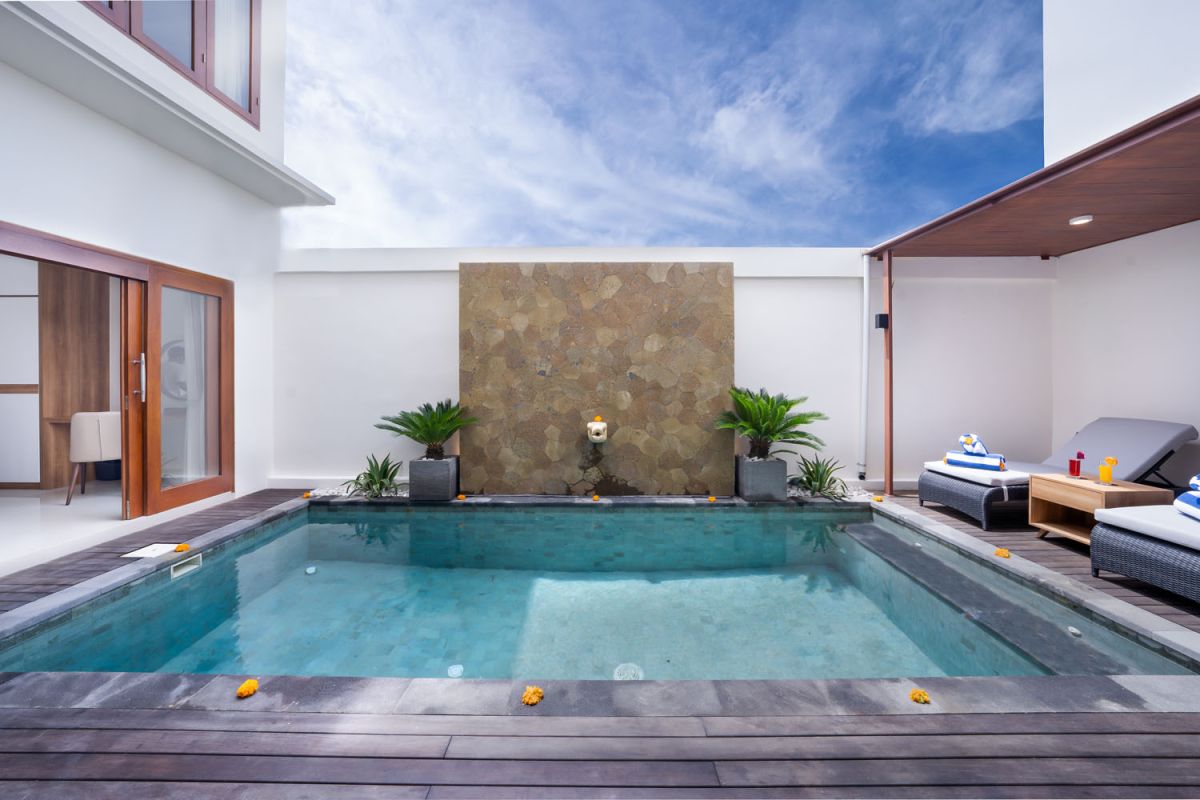 Spacious modern kitchen and dining area with wooden table set for meals, open cabinetry, and sliding glass doors to pool. - Bali Villas