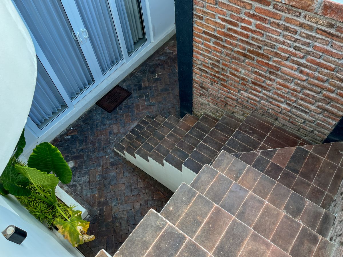 Elegant Bali villa dining room with wooden table set for meal, rattan chairs, and tropical pool view through glass doors. - Bali Villas