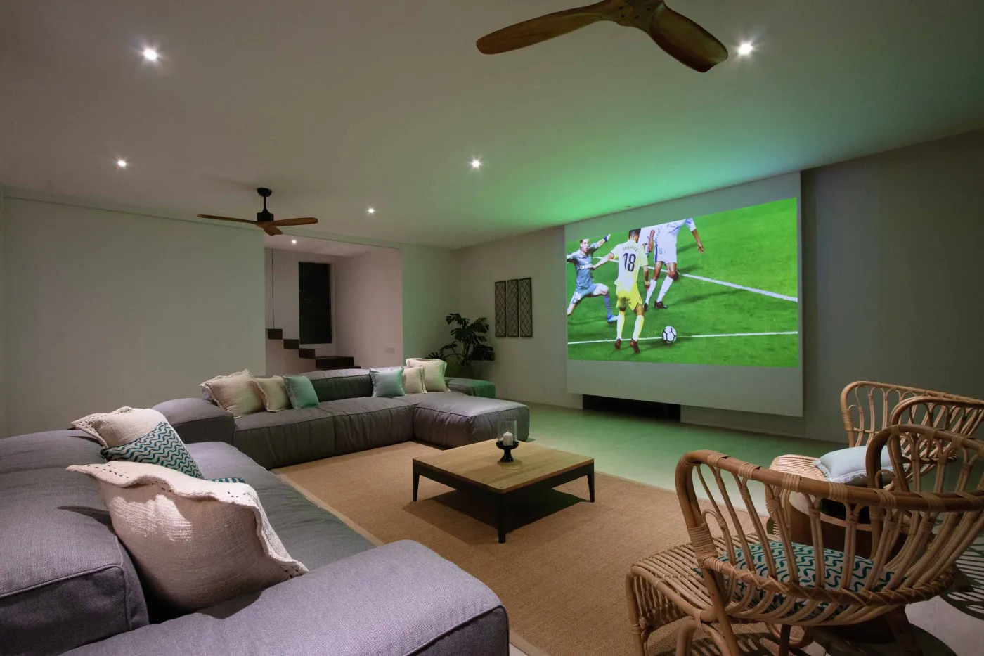 Cozy outdoor balcony lounge with white armchairs, blue tiled table, and potted plants, overlooking tropical palm trees at dusk sunset. - Bali Villas