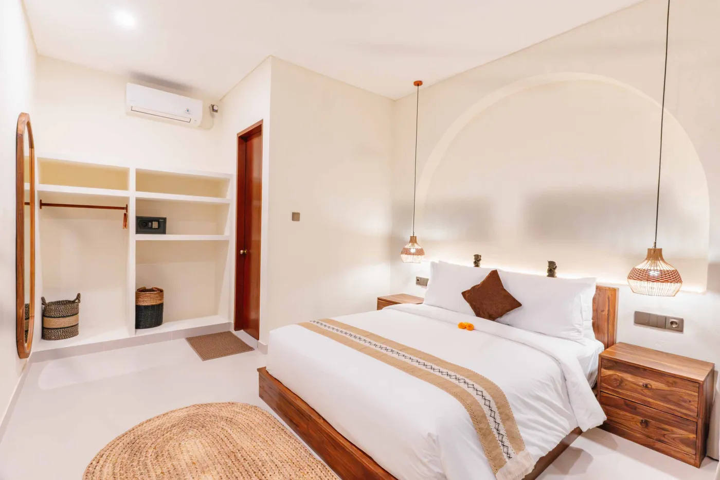 Luxurious spa bathroom with white freestanding bathtub filled with floating red hibiscus petals, wooden mirror, and brass fixtures in soft natural light. - Bali Villas