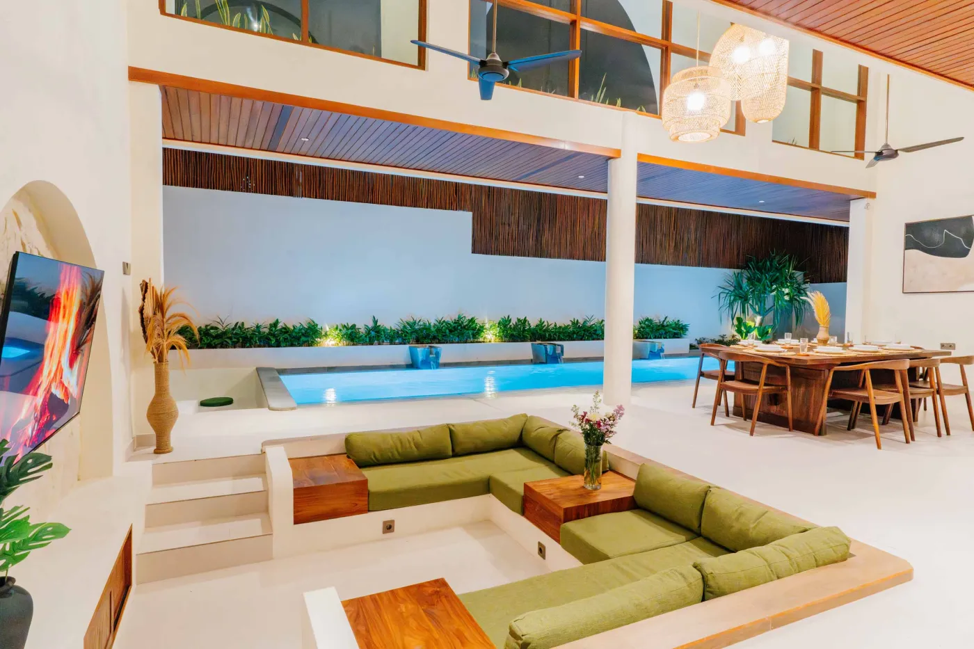 Luxurious spa bathroom with white freestanding bathtub filled with floating red hibiscus petals, wooden mirror, and brass fixtures in soft natural light. - Bali Villas