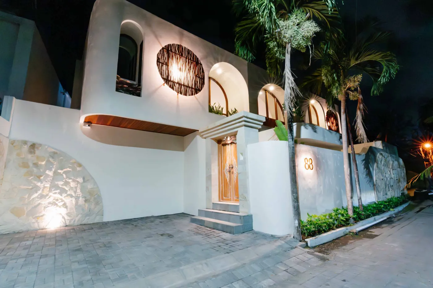 Luxurious spa bathroom with white freestanding bathtub filled with floating red hibiscus petals, wooden mirror, and brass fixtures in soft natural light. - Bali Villas