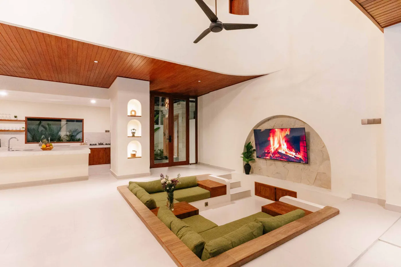 Luxurious spa bathroom with white freestanding bathtub filled with floating red hibiscus petals, wooden mirror, and brass fixtures in soft natural light. - Bali Villas