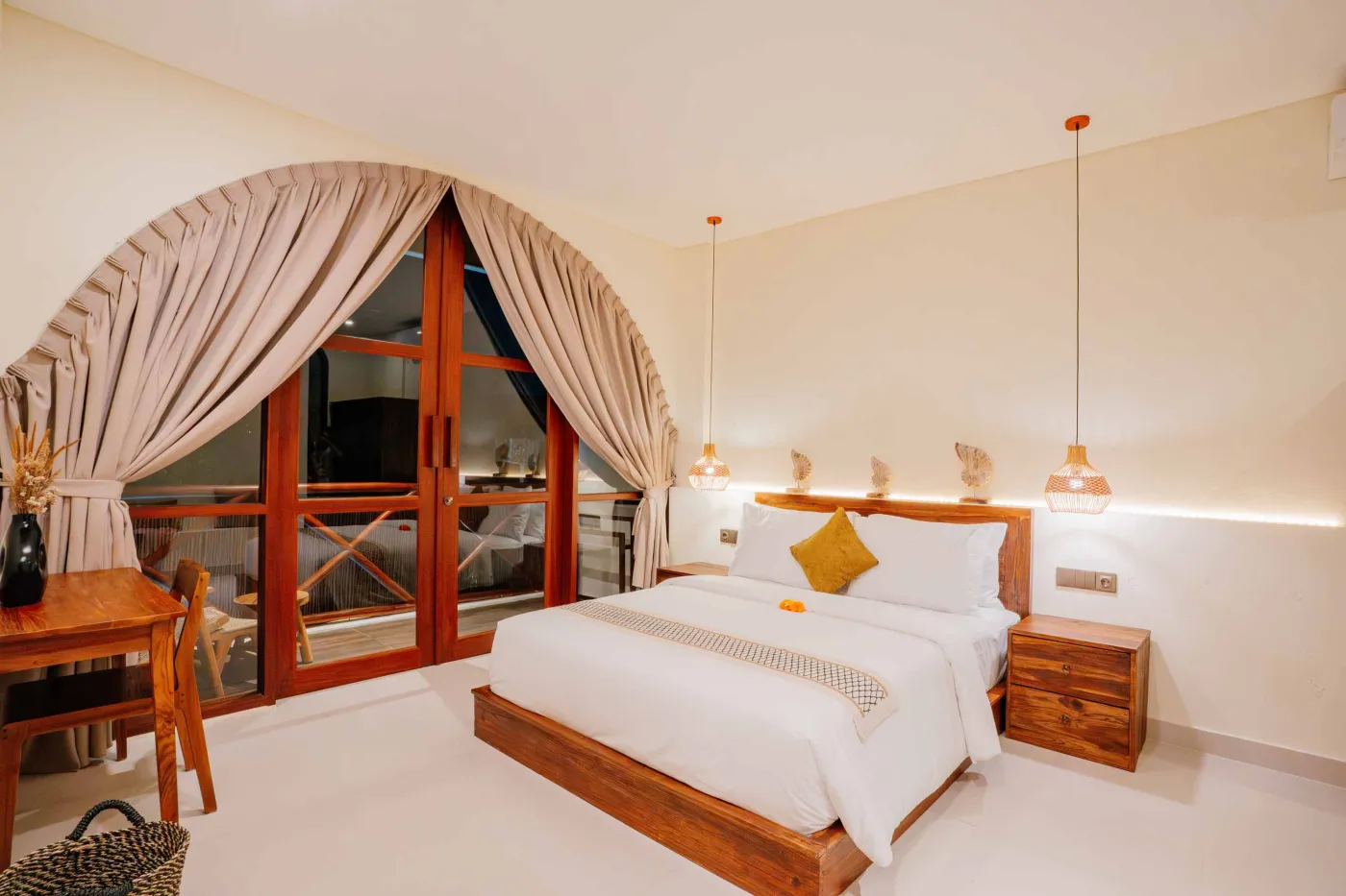 Luxurious spa bathroom with white freestanding bathtub filled with floating red hibiscus petals, wooden mirror, and brass fixtures in soft natural light. - Bali Villas