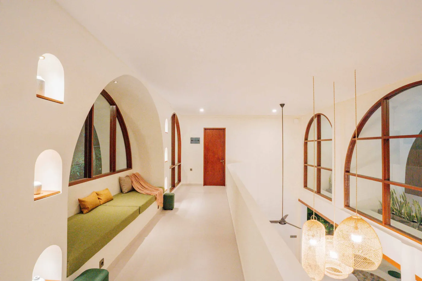Luxurious spa bathroom with white freestanding bathtub filled with floating red hibiscus petals, wooden mirror, and brass fixtures in soft natural light. - Bali Villas