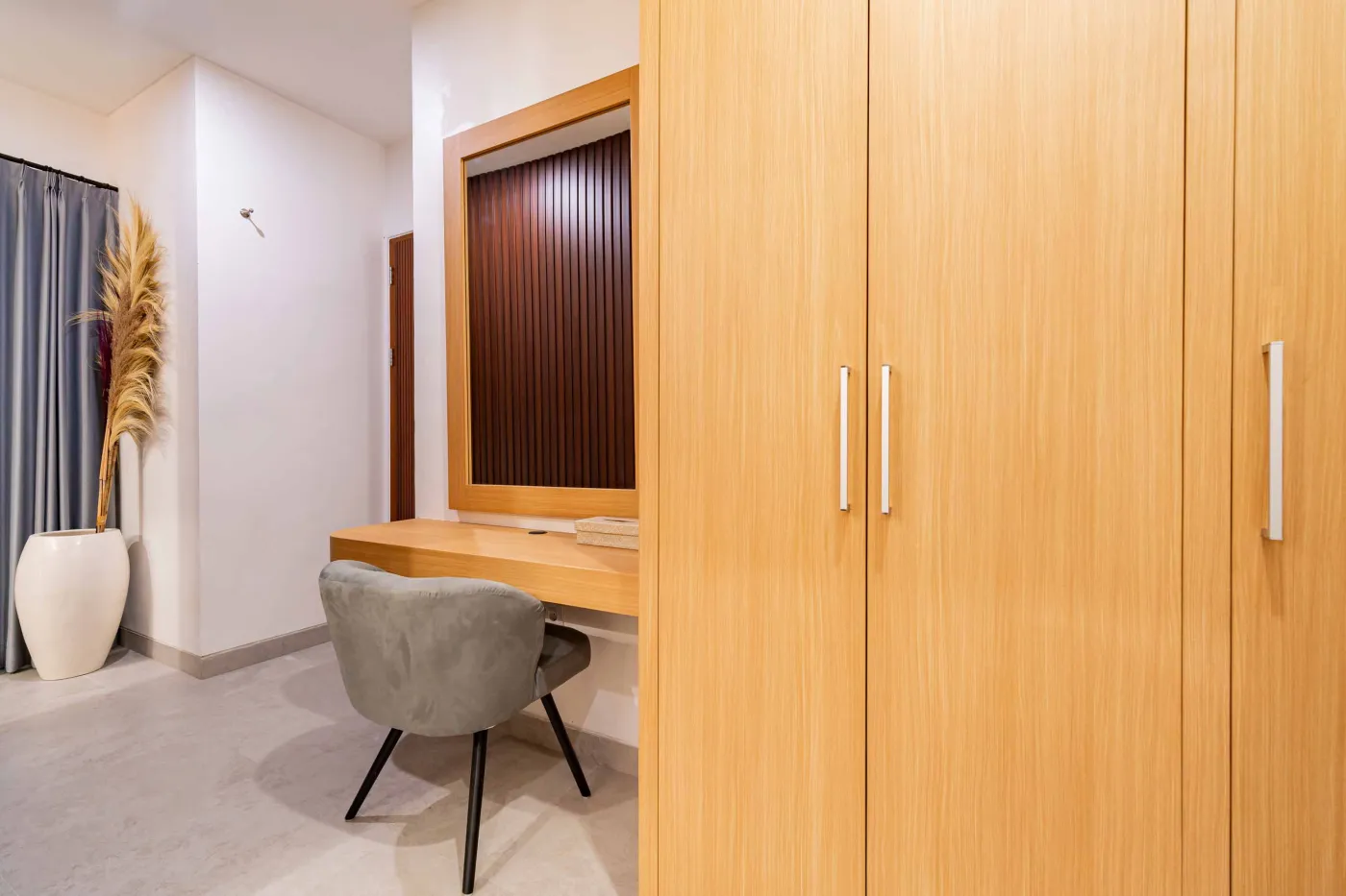 Modern bathroom with round wooden-framed mirror, white vessel sink on black countertop, toilet, and glass shower enclosure. - Bali Villas