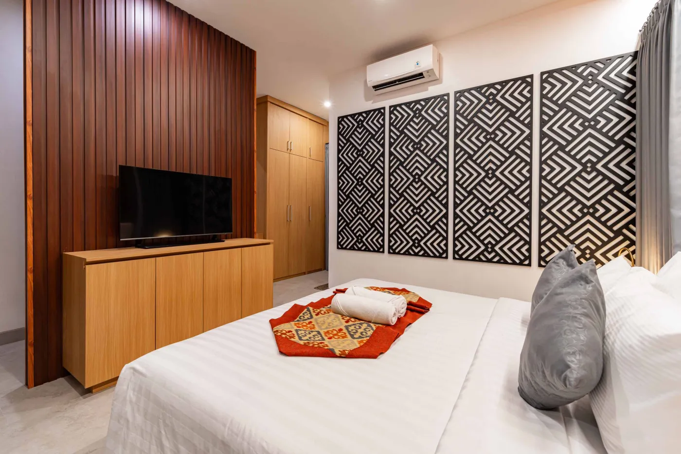 Modern bathroom with round wooden-framed mirror, white vessel sink on black countertop, toilet, and glass shower enclosure. - Bali Villas